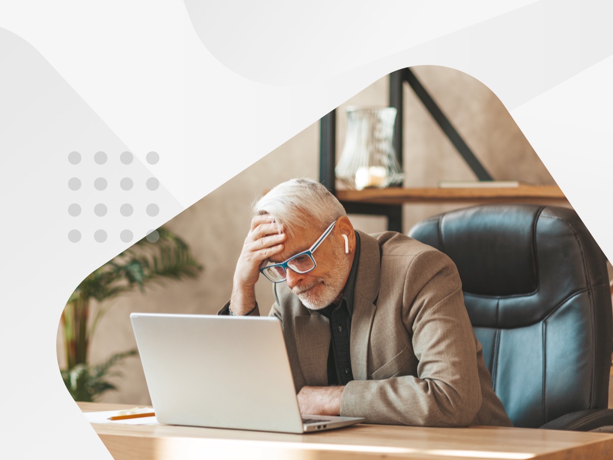 older man looking at laptop concerned with his hand on his forehead