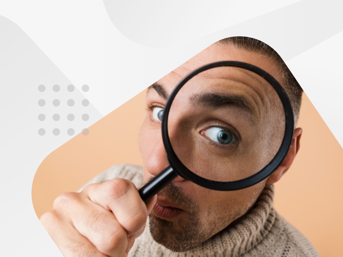 A man intently examines something through a magnifying glass, focusing on the details.