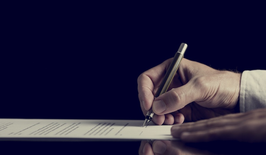 Retro image of a man signing a contract over dark background.