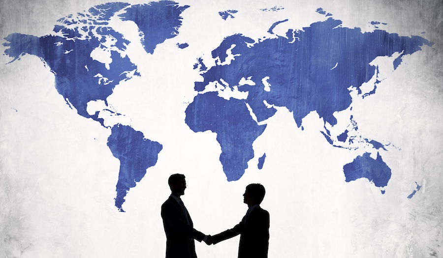 Two Business Men Shaking Hands And A Blue Cartography Of The Wor