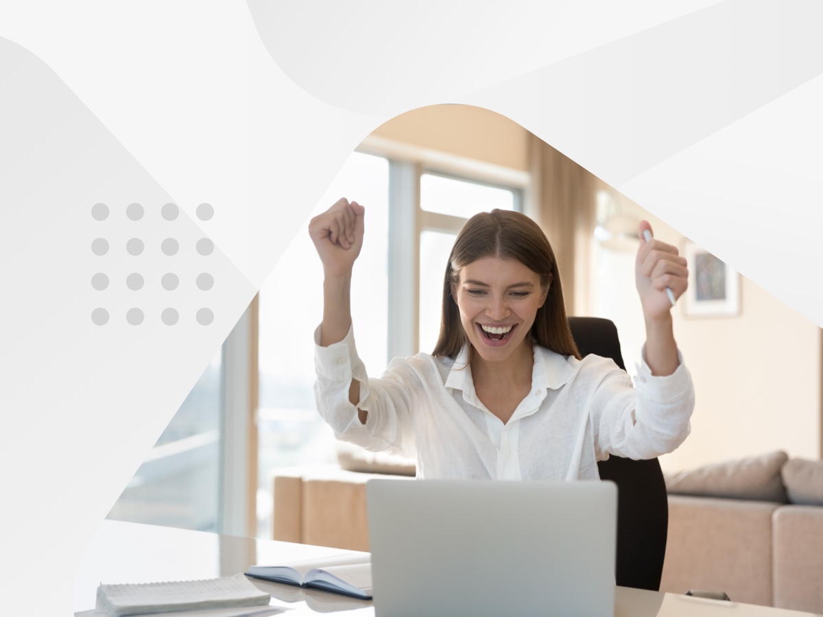 A woman joyfully celebrates on her laptop, expressing happiness and excitement in front of the screen.