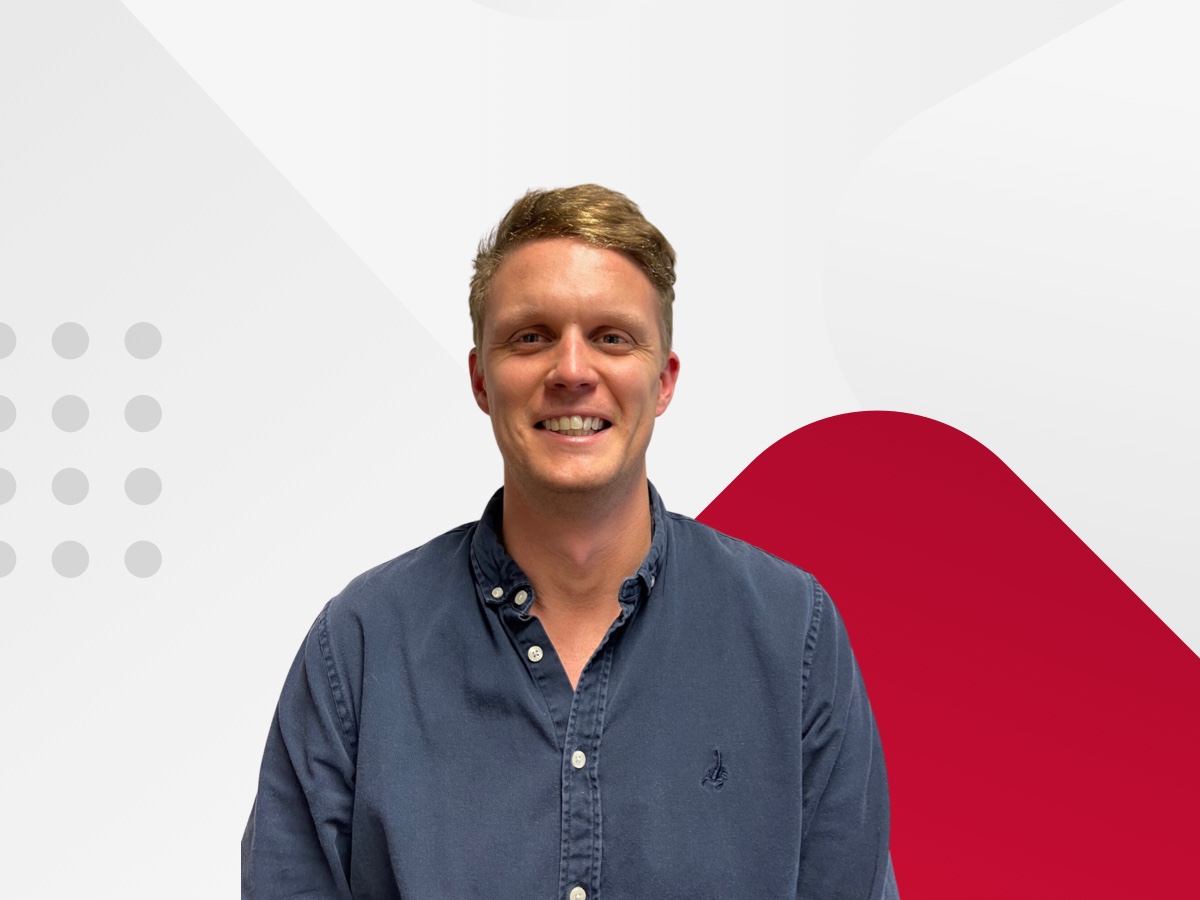 CreditorWatch employee Stirling smiling with a red and white background
